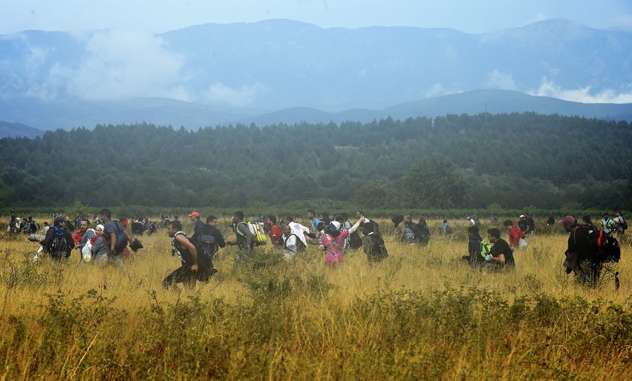 epa04892995 Migrants who waited more then 48 hours on the Greek side of the border line, flee across a field after jumping over razor wire to cross into Macedonia near southern city of Gevgelija, The Former Yugoslav Republic of Macedonia, 22 August 2015.Macedonian special police forces arrived yesterday morning and blocked the illegal border crossing between Macedonia and Greece. They don't give permission to the migrants to pass in Macedonia. Macedonian government has declared emergency situation in the south and north border with Greece and Serbia due to rising number of migrants and fugitives from Syria, Afganistan, Iraq, Pakistan and Somalia. From the beginning of the year to mid-June 2015, nearly 160,000 migrants landed in the southern European countries, mainly Greece and Italy, on their way to wealthier countries in Western and Northern Europe, according to estimates by the International Organization for Migration (IOM). EPA/GEORGI LICOVSKI